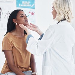 Photo of a doctor examining a woman's throat in an examination room