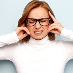 Photo of a woman grimacing with her hands over her ears