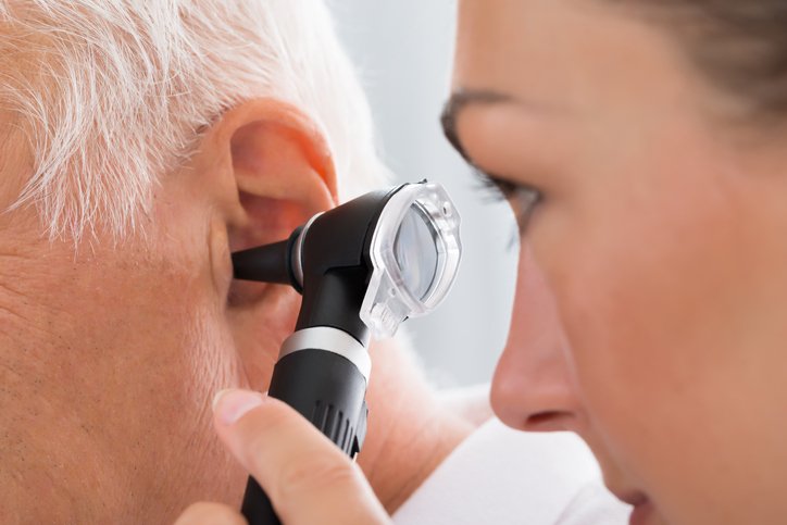 An audiologist examining a patient with an otoscope