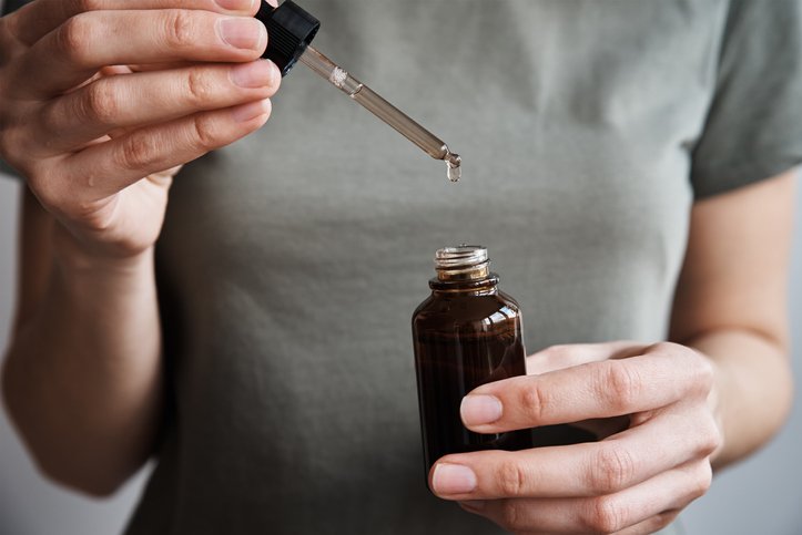 Photo of a woman extracting liquid from a bottle with a dropper or pippete