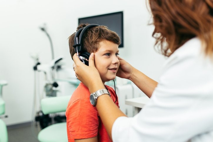 Photo of a provider placing headphones on a child in an exam room