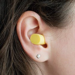 Photo of an ear plug placed in a woman's ear canal