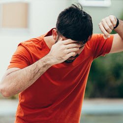 Photo of a man suffering from dizziness with difficulty standing up while leaning on wall